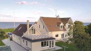 Een tweelaags huis met een balkon, een garage en uitzicht op zee.