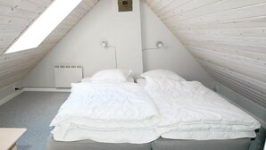 Een kleine zolderkamer met twee eenpersoonsbedden, een schuine kap en een dakraam.