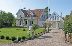 Traditional two-story home with a pitched roof and balcony, set amidst a well-manicured lawn.