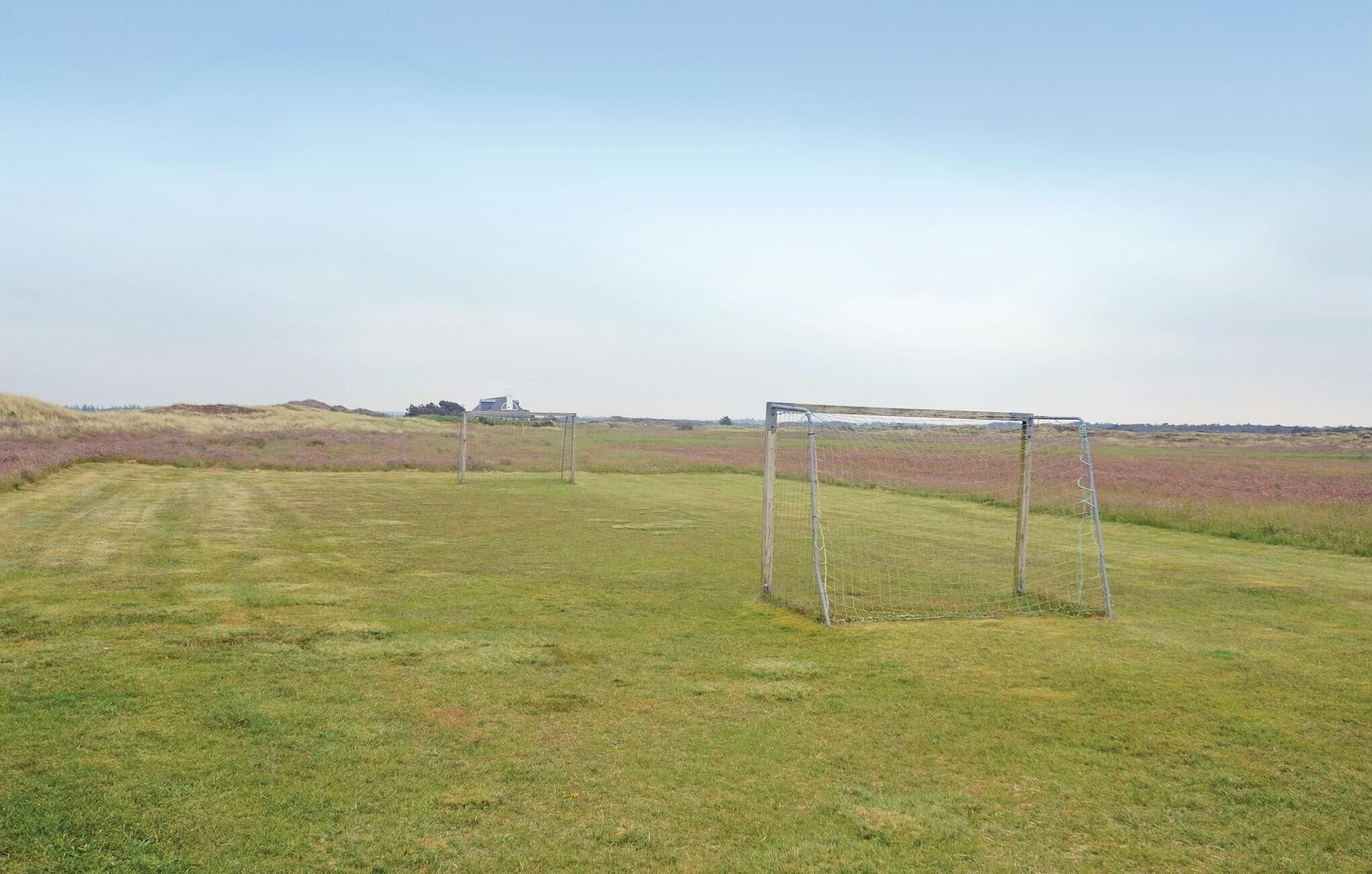 Ein Fußballtor in einem grünen Rasenfeld unter blauem Himmel.