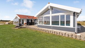 A modern house with a large glass extension, a patio with outdoor furniture, and a swimming pool. - Gorgeous home in Thisted with sauna (Thisted)