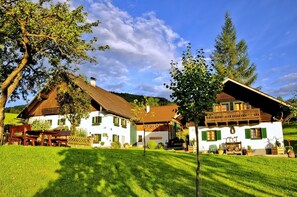 A traditional chalet-style building with a sloped roof, wooden shutters, and a well-maintained lawn. - Apartment Attersee - Apartment on the farm Margarethengut am Attersee (Buchenort)