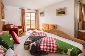 A bedroom with a wooden bed, a wooden dresser, a radiator, a window with curtains, and a view of the outdoors.