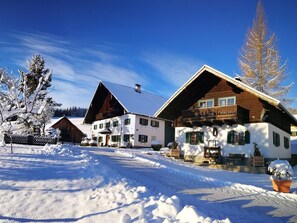 Ett snötäckt landskap med traditionella trähus, en klar himmel och ett snötäckt träd.