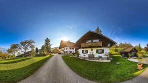 A rural house with a paved driveway, a balcony, and a well-maintained lawn. - Apartment Attersee - Apartment on the farm Margarethengut am Attersee (Buchenort)