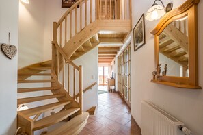 A wooden staircase leading to a second floor, a hallway with a radiator, and a large mirror on the wall. - Apartment Attersee - Apartment on the farm Margarethengut am Attersee (Buchenort)