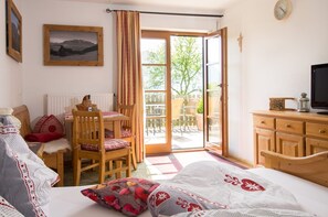 A bedroom with a bed, a desk, a chair, a television, and a view of the outdoors.