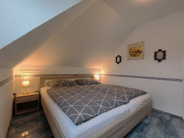 A bedroom with a bed, bedside tables, and wall-mounted lights. - Spies: Holiday apartment for 2 in the middle of the green inland - Holiday apartment (Sieverstedt)