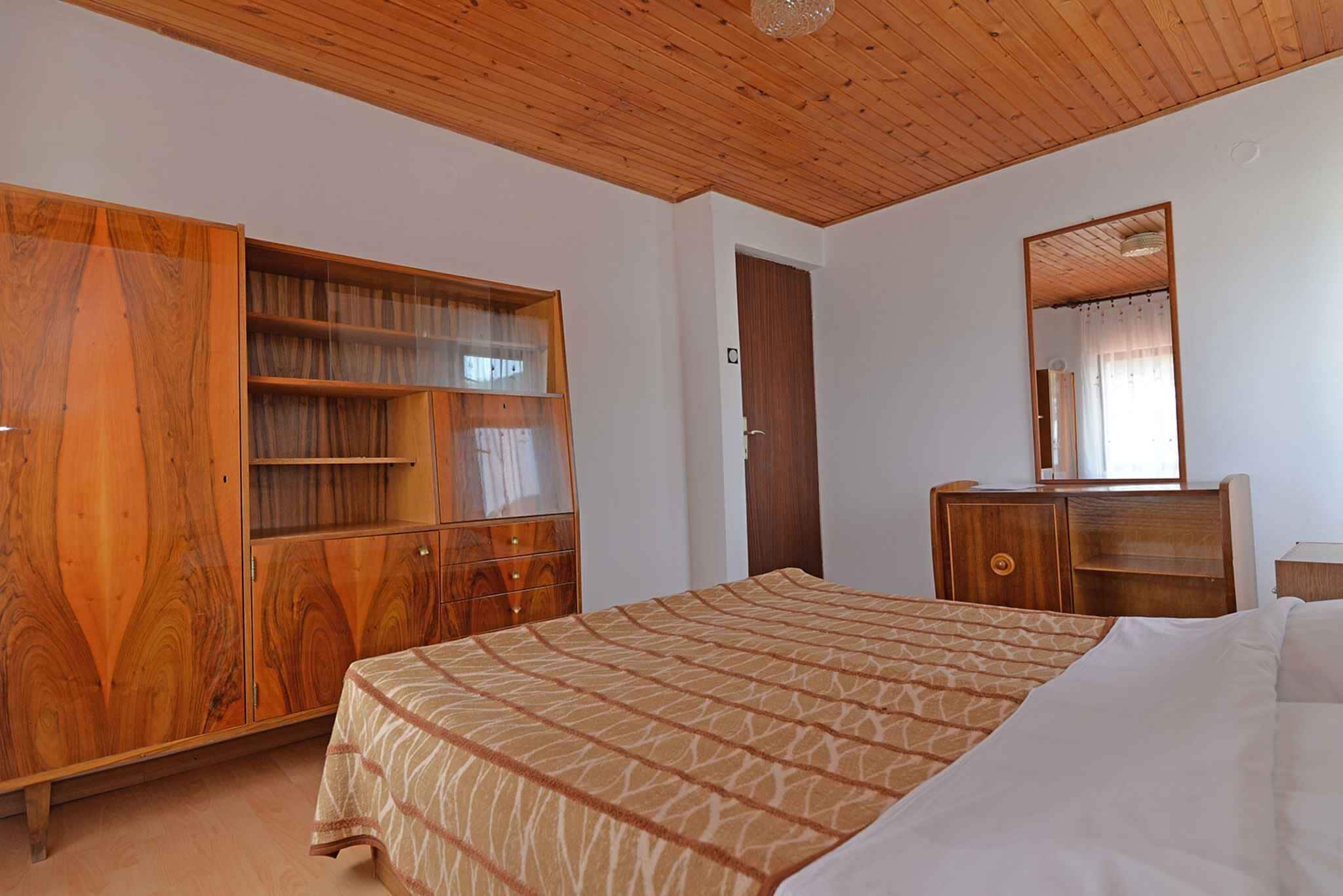 Un dormitorio con cama, armario de madera y espejo.
