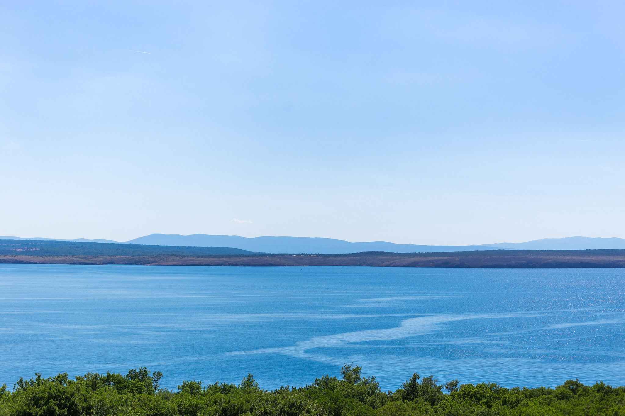 Une vaste étendue d'eau, avec une côte lointaine et un ciel dégagé.