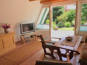 Ein gemütliches Wohnzimmer mit Fernseher, Holztisch und einer Couch.