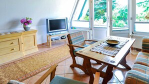 Un espace repas comprenant une table en bois, des chaises et un téléviseur.
