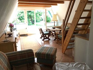 Ein gemütliches Zimmer mit Esstisch, Stühlen, einer Couch und einer Treppe.