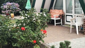Une terrasse avec des chaises blanches, une table et un parasol vert.