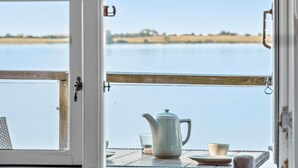 A view from a room with a window overlooking a calm body of water and a distant landscape.