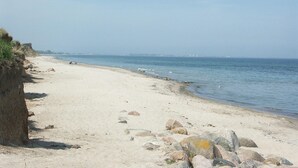 A sandy beach with scattered rocks and a clear view of the ocean. - Beach front home in Süssau/Ostsee (Süssau/Ostsee)