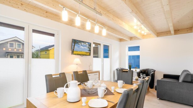 A dining area with a wooden table set for four, a coffee pot, and a painting on the wall. - Beach front home in Süssau/Ostsee (Süssau/Ostsee)