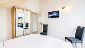 A bedroom with a bed, two chairs, a TV, and a sliding door leading to a balcony. - Beach front home in Süssau/Ostsee (Süssau/Ostsee)