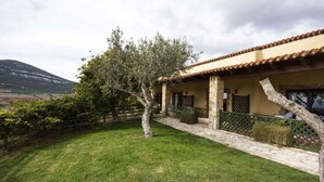 A villa with a stone facade, a tiled roof, and a well-maintained lawn. - Holiday apartment with climate control system (Alghero)