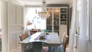 A dining area with a chandelier, a table set for four, and a cabinet with glass doors displaying dishes and glassware. - Lovely home in Sollebrunn with WiFi (Sollebrunn)