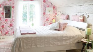A bedroom with a sloped ceiling, floral wallpaper, a bed with white bedding, a green plant, and a window with a view of greenery. - Lovely home in Sollebrunn with WiFi (Sollebrunn)