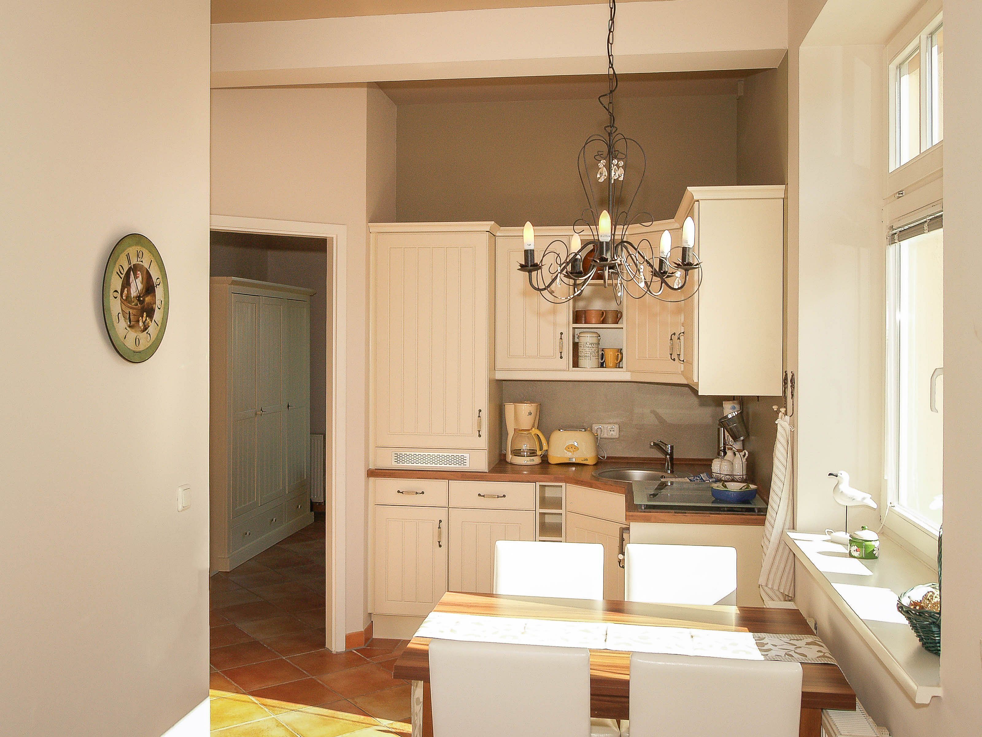 A kitchen with white cabinets, a chandelier, and a dining table with chairs.
