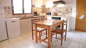 A compact kitchen with a dining table, chairs, a microwave, a stove, and a dishwasher. - 3 bedroom beautiful home in La Tranche sur Mer (La Tranche sur Mer)