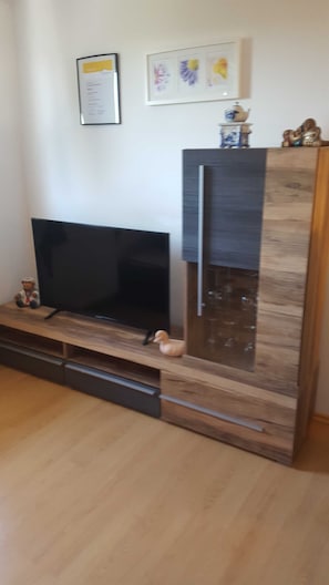 Una sala de estar moderna con un televisor de pantalla plana, un mueble de madera y objetos decorativos.