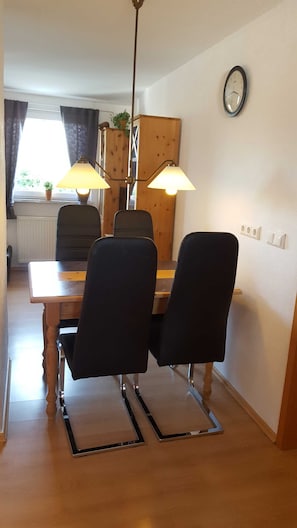 A dining area with a wooden table, two black chairs, and two table lamps.