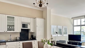 Cocina moderna con armarios blancos, una mesa de comedor con sillas, una araña y obras de arte en la pared.
