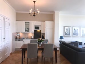 Una cocina moderna con armarios blancos, una mesa de comedor con sillas y un candelabro.