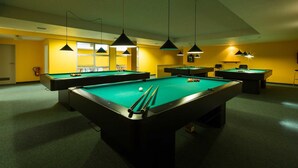 Ett biljardhall med flera biljardbord, takbelysning och en brandsläckare.