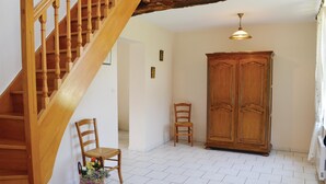 A wooden staircase leading to a room with a tiled floor, a wooden wardrobe, and a chair with a basket of flowers. - 3 bedroom stunning home in Chigny (Chigny)