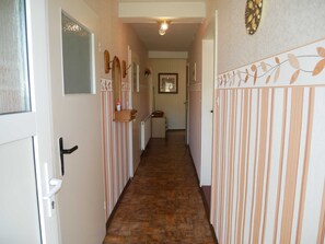 Um corredor estreito com paredes listradas, uma porta de madeira e um radiador.