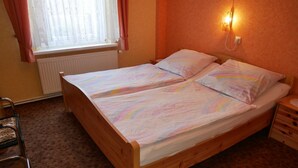 A single-bed room with a wooden frame, a radiator, a chair, and a wall-mounted light fixture. - Vacation apartment Kasch - Holiday apartment in the countryside (Krummin)