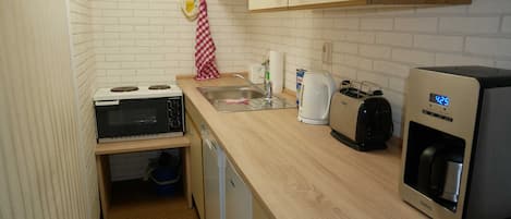 A compact kitchen with a built-in stove, a coffee maker, a toaster, and a water dispenser.