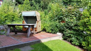 A garden with a wooden table and a covered seating area.