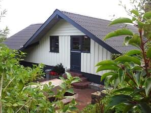 A house with a gabled roof, a front porch with steps, and a brick pathway leading to the entrance.