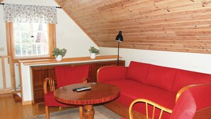 A cozy room with a red sofa, a wooden table, and a window with blinds. - Gorgeous home in Ruda with kitchen (Ruda)