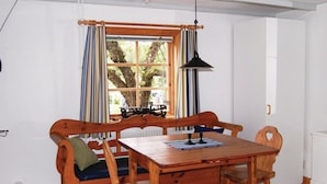 A wooden dining table with benches, a hanging pendant light, and a window with striped curtains. - Gorgeous home in Ruda with kitchen (Ruda)