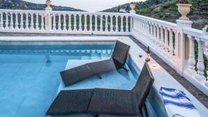 A pool area with two lounge chairs and a small table, surrounded by a white balustrade. - Amazing home in Corumbela (Corumbela)