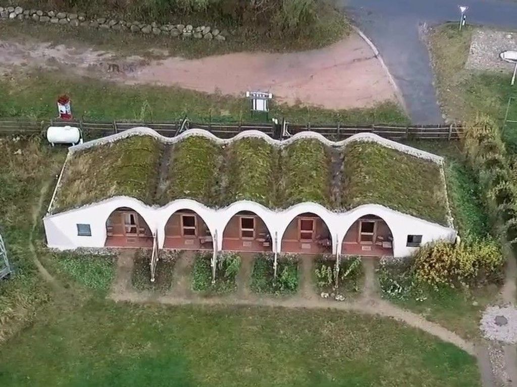 A white building with a unique curved roof and multiple arched windows.