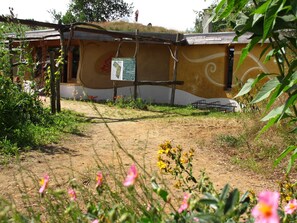 Un edificio con una pared exterior curva distintiva, un cartel y un camino de tierra que conduce a él.