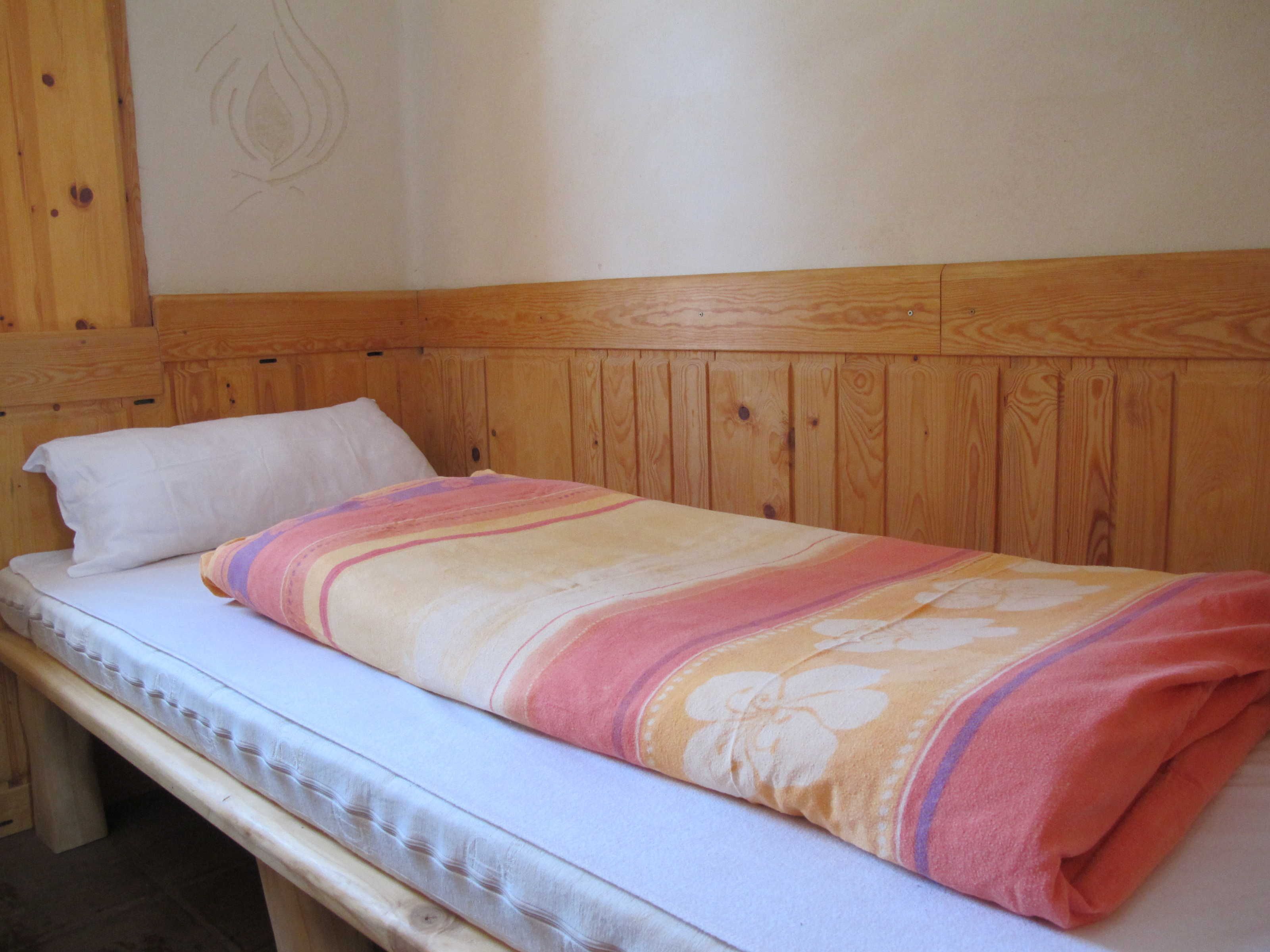 A single bed with a wooden headboard and a white pillow.