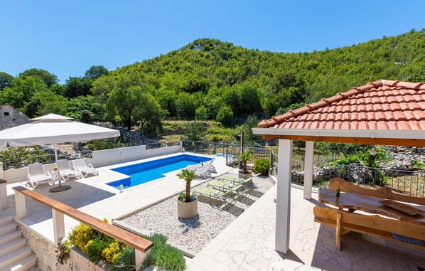 Ein Poolbereich mit Liegestühlen und einer Pergola.