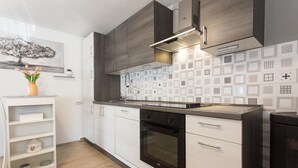 A modern kitchen with white cabinetry, a black oven, and patterned backsplash tiles. - Amazing home in Blato na Cetini (Blato na Cetini)