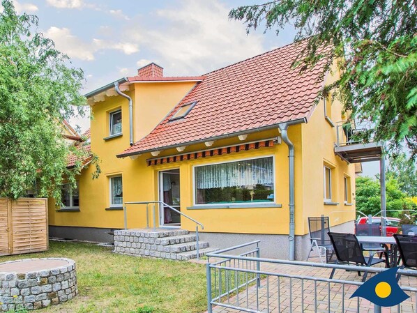 A yellow building with a red-tiled roof, a stone staircase, and a small outdoor seating area.
