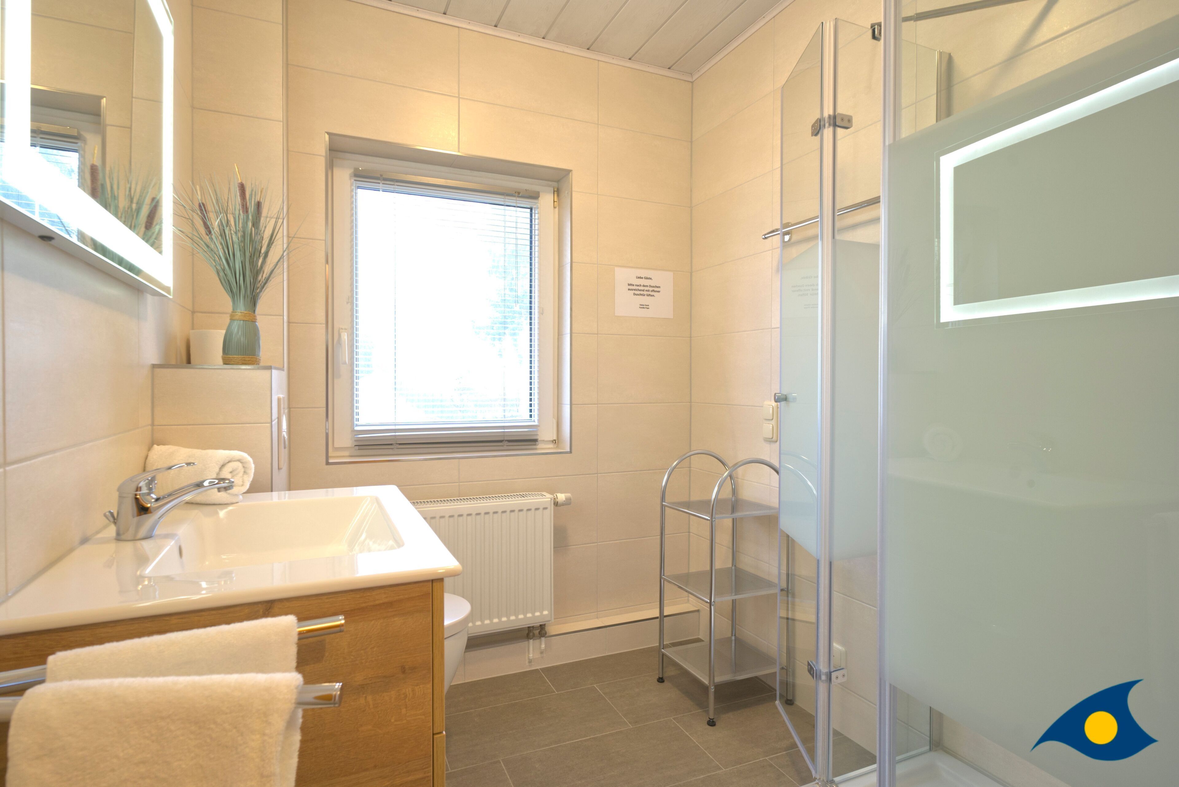 Un baño moderno con lavamanos, espejo y cabina de ducha de vidrio.