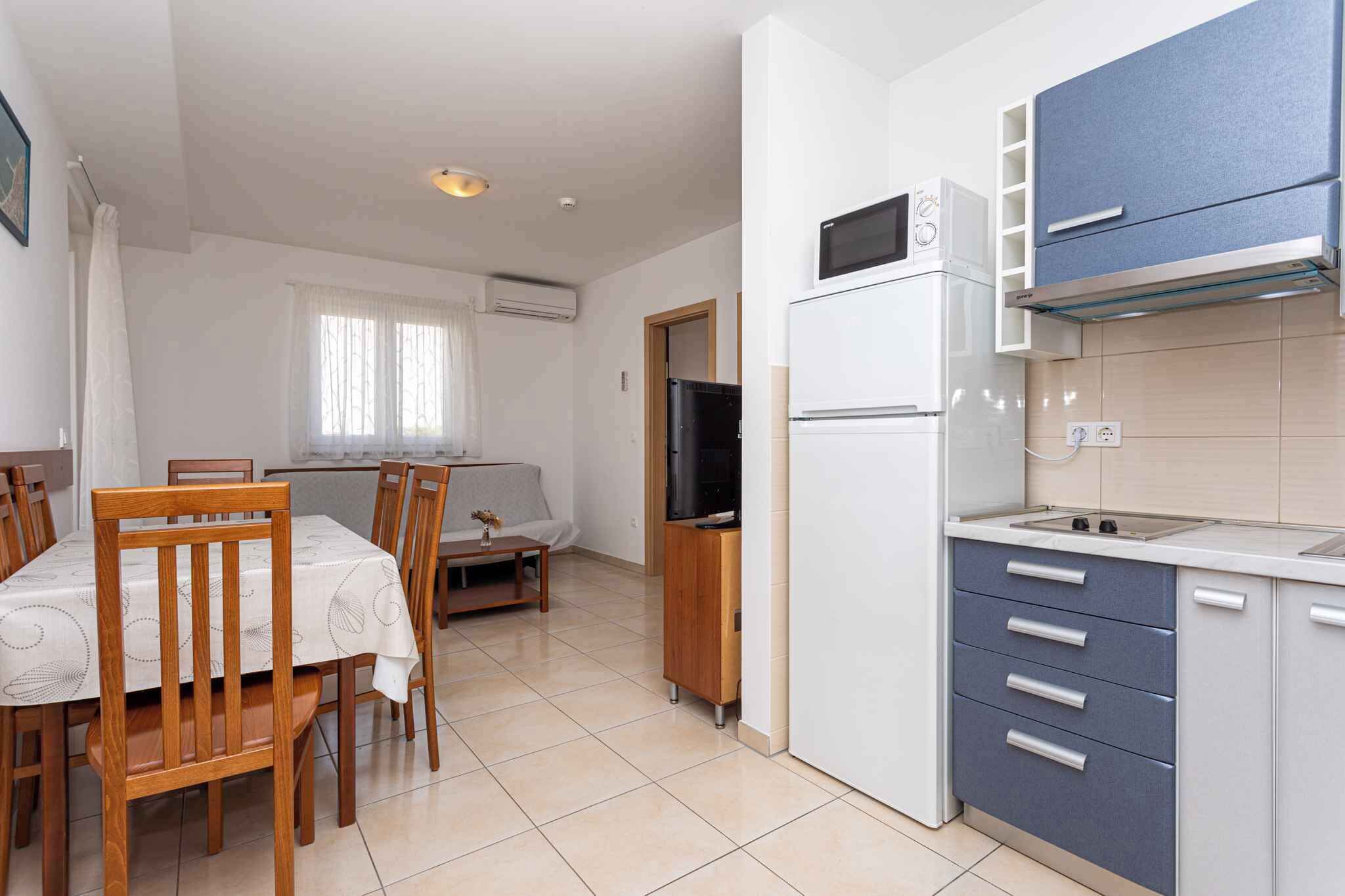 A compact kitchen with a refrigerator, microwave, and stove. There is a dining area with a table and chairs.
