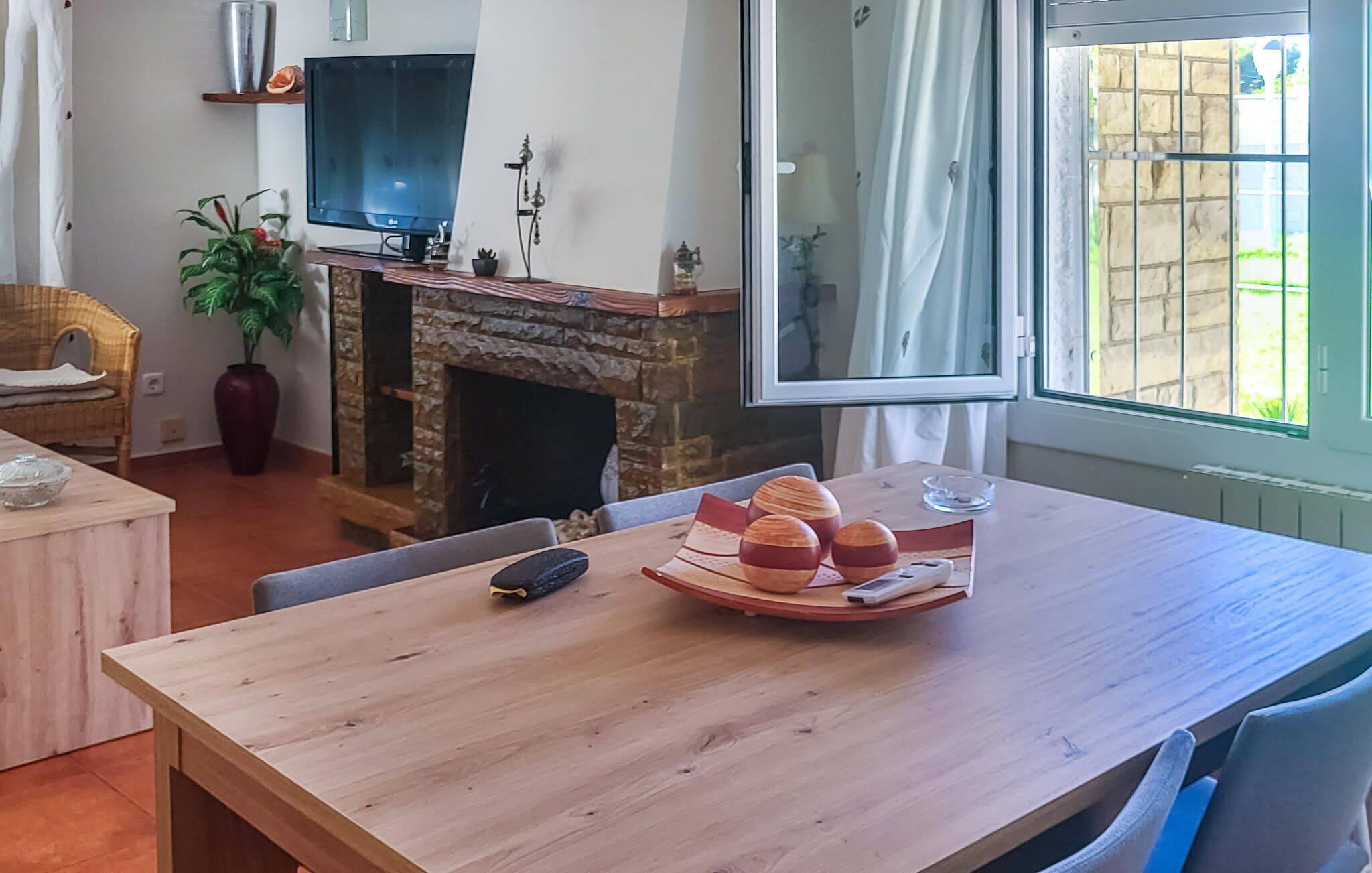 Una sala de estar acogedora con chimenea, televisor y una mesa de comedor con pan y un control remoto.